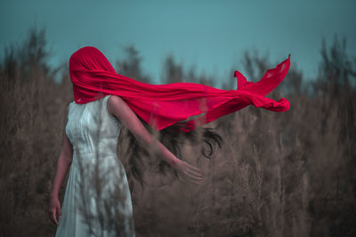 Side view of woman with red umbrella on field