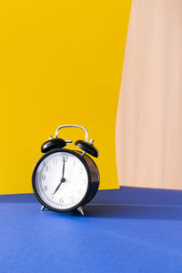 Close-up of clock on table against yellow background