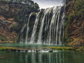 Scenic view of waterfall against sky