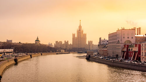 View of river and buildings against sky during sunset