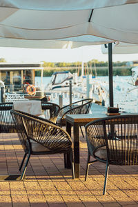 Outdoor terrace of a restaurant or cafe. blankets hang on the chairs. background the yacht club.