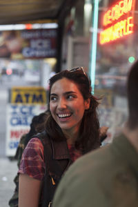 Portrait of smiling woman in city at night