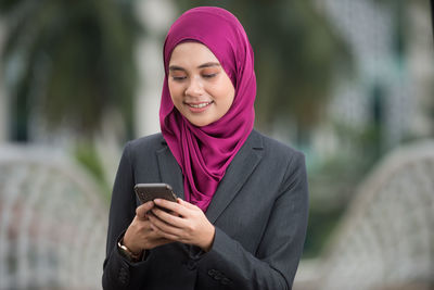 Portrait of a young woman using mobile phone outdoors