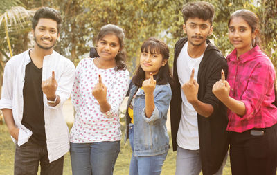 Portrait of people showing finger while standing outdoors