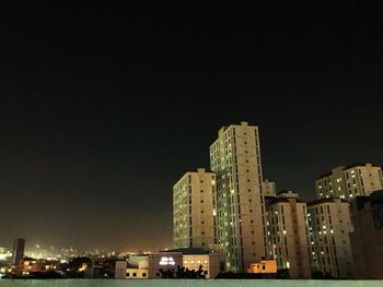 Illuminated buildings against clear sky at night