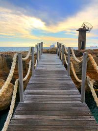 Wooden pier on sea against sky during sunset