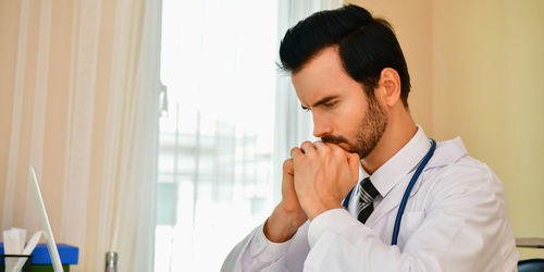 Close-up of thoughtful male doctor sitting in clinic
