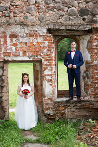 Bride and groom standing at abandoned wall