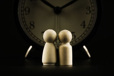 Close-up of clock on table against black background