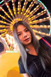 Portrait of smiling young woman in amusement park at night