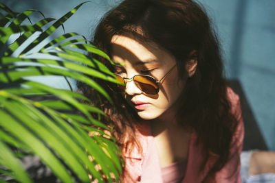 Close-up of woman wearing sunglasses sitting by plants
