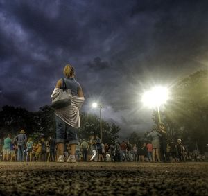 People standing on field against sky at night