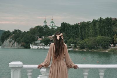 Rear view of woman standing against lake