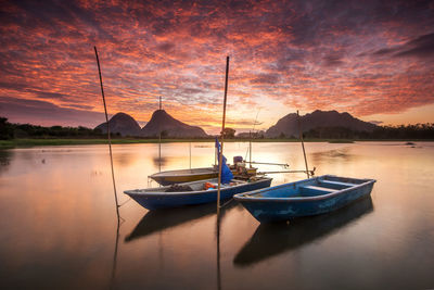 Boat moored on sea against sky during sunset