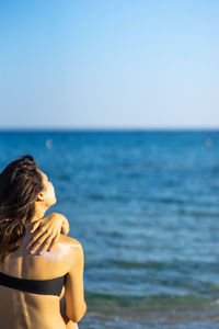 Woman by sea against clear sky