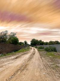 Dirt road along landscape and against sky