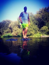Rear view of man standing by lake against sky