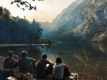 Rear view of friends sitting at lakeshore