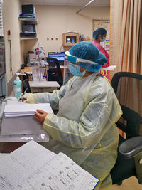 Rear view of people working on table