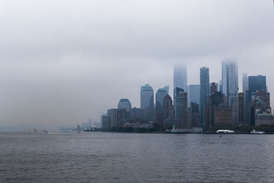 Sea by buildings against sky in city