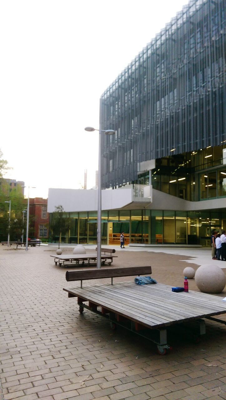 building exterior, architecture, built structure, clear sky, city, chair, empty, modern, day, absence, sky, office building, table, window, sunlight, copy space, building, outdoors, glass - material, city life