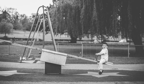 Full length of boy playing on seesaw at playground