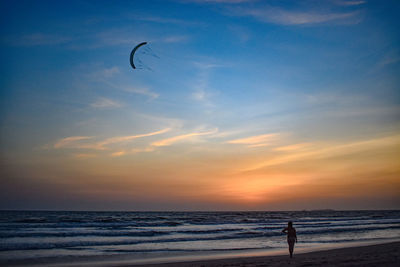 Silhouette person on beach against sky during sunset