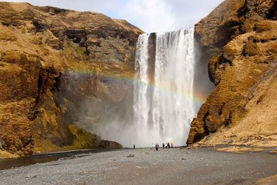 People standing against waterfall