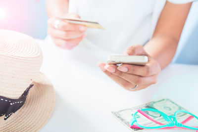 Close-up of woman using mobile phone on table