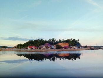 Island with scenic view of lake by building against sky