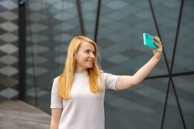 Young blond woman making selfie on smartphone for her followers. young influencer girl. 