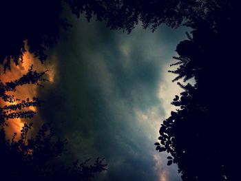 Low angle view of silhouette trees against storm clouds