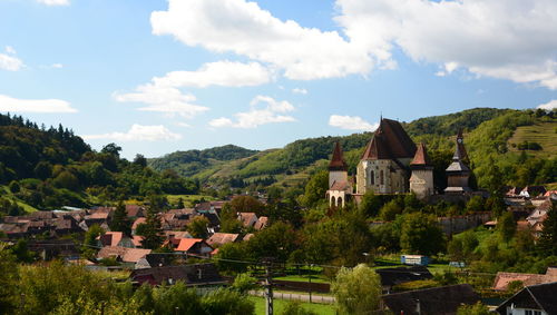 Houses by trees and buildings against sky
