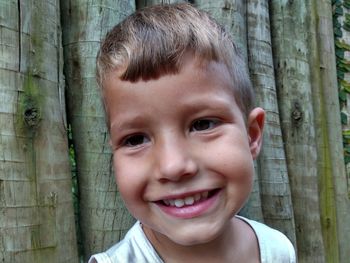 Close-up of happy boy against tree trunk