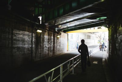 Rear view of man walking in illuminated corridor