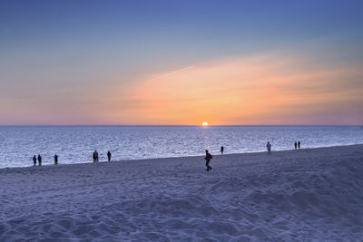 People at sandy beach during sunset