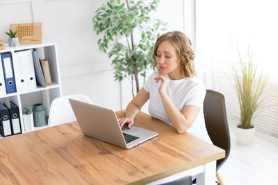 Young woman using phone while sitting on table