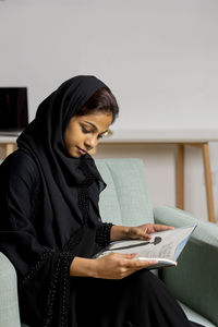 Young woman looking down while sitting on table