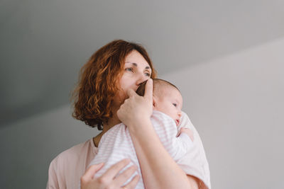 Portrait of happy mum holding infant child on hands.