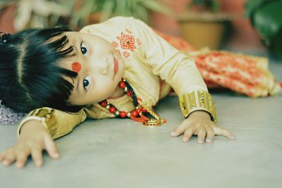 Close-up portrait of cute girl wearing traditional clothing while lying on floor