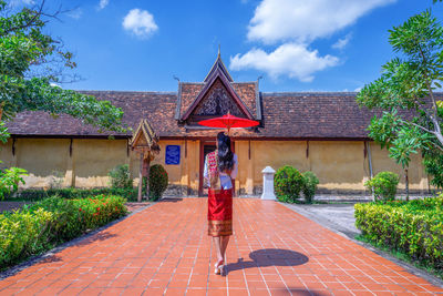 Asian female tourists dressed in lao national costumes walk in front of sisaket temple in vientiane