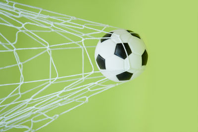 Close-up of soccer ball in net against green background