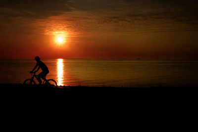 Silhouette of man in sea at sunset