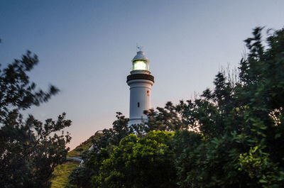 Low angle view of lighthouse amidst trees and buildings against sky
