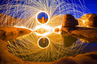 Men with wire wool standing by lake at night