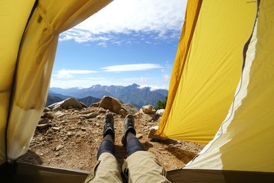 Low section of person standing at tent against sky