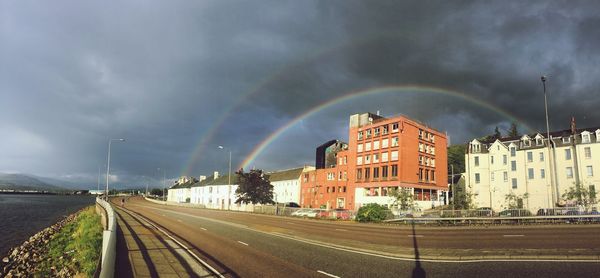 View of rainbow over road against cloudy sky