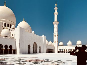 Man photographing mosque against sky