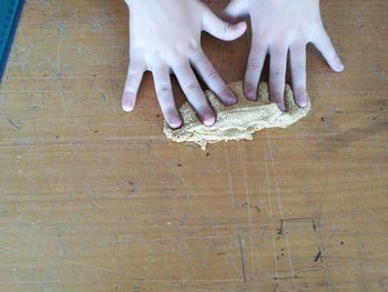 Cropped hand of child playing with clay on table