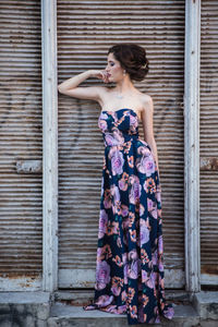 Young woman standing against brick wall